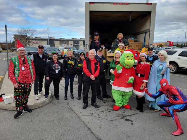 Group of people behind food and toy truck drive, most of them wearing Holiday and children's cartoon characters